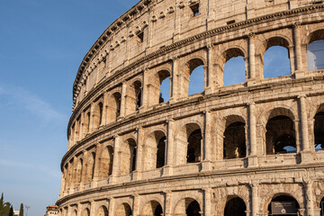 Impressive exterior view of Colosseum in Rome with blue sky in background.