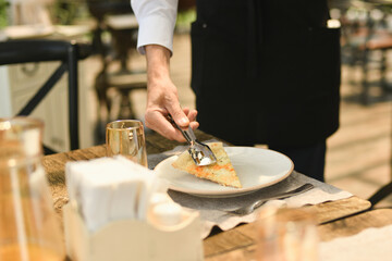 The waiter punishes a piece of cheese on a plate