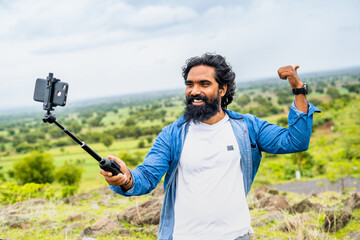 happy smiling travel vlogger on top of mountain recording video on mobile phone for soical media -...