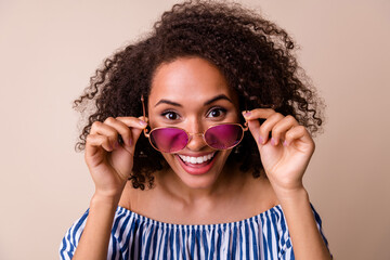 Photo of shiny excited girl dressed off shoulders clothes arms dark eyewear smiling isolated beige color background