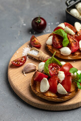 Open sandwiches with cherry tomatoes, mini mozzarella, fresh basil leaves, caprese on bread, Traditional italian appetizer or snack, antipasto. banner, menu, recipe place for text, top view