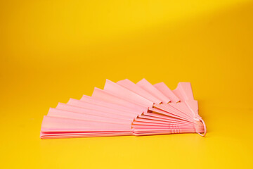 Pink fan on a yellow background. - Summer concept