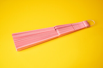 Pink fan on a yellow background. - Summer concept