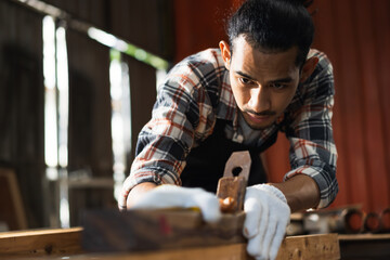 Young Asian man carpenters are using spokeshave to decorate the woodwork in woodcraft carpentry workshop.