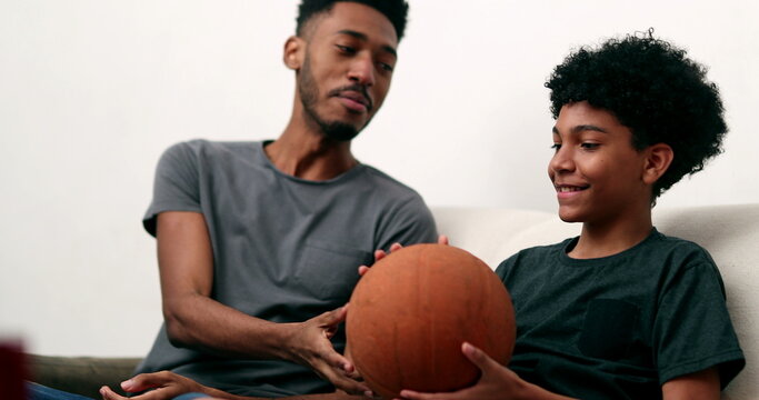 Older Brother Teaching Younger Sibling To Spin Basketball With Finger. Two Brothers Bonding