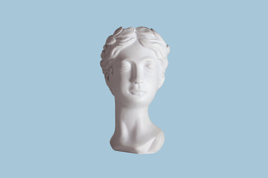 Female antique statue's head isolated on a blue color background