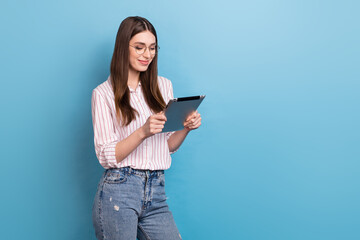 Fototapeta premium Photo of sweet shiny woman wear striped spectacles reading modern device empty space isolated blue color background