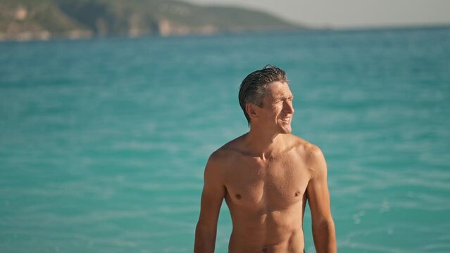 slow motion of enjoyed athletic man going out of turquoise water of mediterranean sea in Oludeniz Beach in Aegean Sea after swimming. Summer tourist Season Fethiye, Mugla Turkey