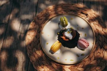 Fototapeta premium Three macaroons served on plate on wooden table in outdoor cafe
