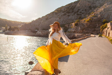 Plus size woman with beautiful blond hair , wearing  boho style clothes, maxy dress,  enjoy the time in nature against blue water of sea