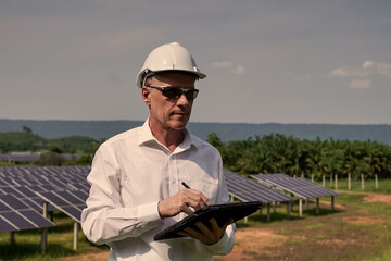 Solar farm (solar panels) with engineers using a tablet to check the system's operation....