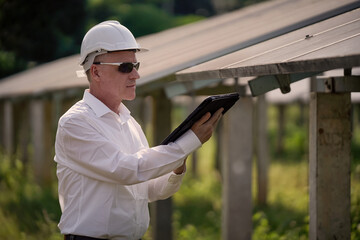 Solar farm (solar panels) with engineers using a tablet to check the system's operation....