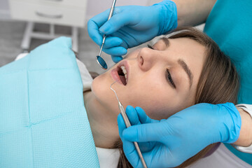 photo of a pretty woman being examined by a dentist with dental instruments in a dental chair.