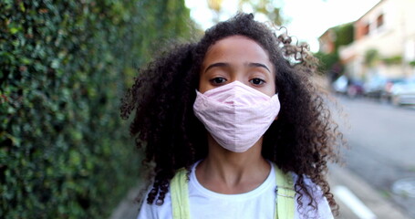 Mixed race girl wearing covid-19 face mask staring at camera