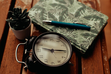 Close-up of a clock and a diary with a pen, concept of time and script.