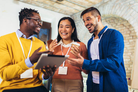 Happy business colleagues using digital tablet while standing in a office