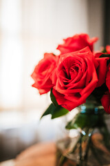 Red roses in vase in a window 