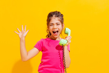 Emotional little girl, kid in casual style clothes isolated over bright yellow background. Concept of children emotions, fashion, beauty, school and ad, retro style