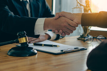 Fototapeta premium Businessmen shake hands after consulting the law from lawyers, judges, and legal counsel. Consulting services on various contracts to plan a court case with hammers and scales next to