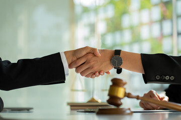 Businessmen shake hands after consulting the law from lawyers, judges, and legal counsel. Consulting services on various contracts to plan a court case with hammers and scales next to