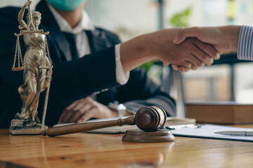 Businessmen shake hands after consulting the law from lawyers, judges, and legal counsel. Consulting services on various contracts to plan a court case with hammers and scales next to