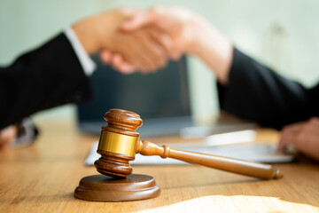 Businessmen shake hands after consulting the law from lawyers, judges, and legal counsel. Consulting services on various contracts to plan a court case with hammers and scales next to