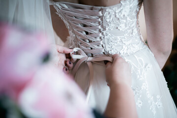Bridesmaid lacing brides wedding dress