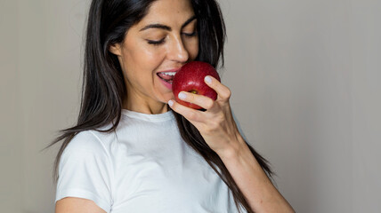 Beautiful Young Woman Eating Red Apple. Healthy Eating and Dental Care Concept 