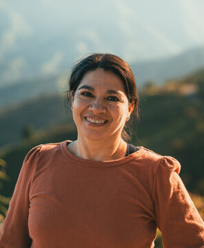 portrait of middle-aged latin lady, 50 years old, smiling on an out of focus background in the equatorial highlands on a sunny day, selective focus