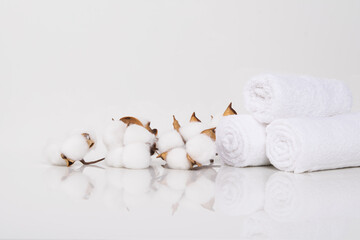 on a white table with a reflection, towels rolled up for spa treatments