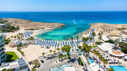Aerial bird's eye view of Vathia Gonia beach, Ayia Napa, Famagusta, Cyprus. Landmark tourist attraction rocky bay with golden sand, sunbeds, sea restaurants in Agia Napa on summer holidays from above