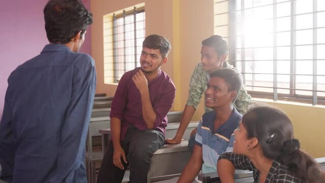 Group od happy smiling college students having chat with each other at classroom during leisure - concept of taking break, friendship and knowledge