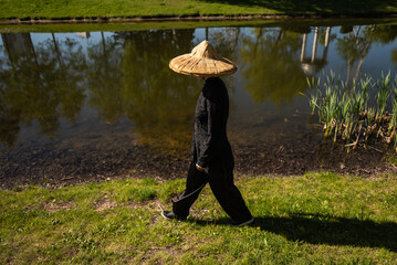 Asian woman with hat practicing taijiquan outdoors, chinese martial arts, healthy lifestyle concept.