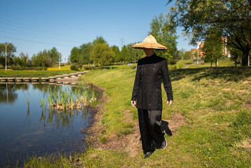 Asian woman with hat practicing taijiquan outdoors, chinese martial arts, healthy lifestyle concept.