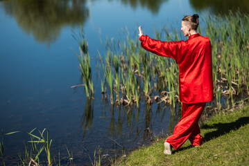 Asian woman in red kimano practicing taijiquan outdoors, chinese martial arts, healthy lifestyle...
