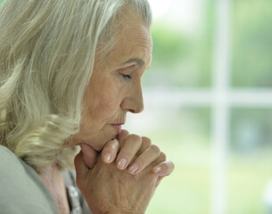 Close up portrait of sad  senior woman praying