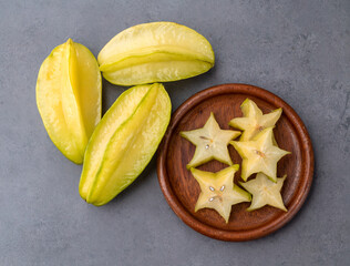 Starfruits with slices in a plate over stone background