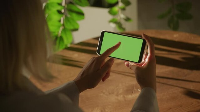 Handheld close up of a caucasian woman hand swipe on a smart phone with green screen croma key