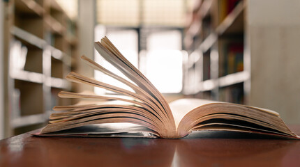 An open book or textbook in the library with light from the window on the reading table and the...