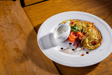 Fried fish in batter with salmon, basil, flower petals and caviar, lemon