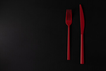 Red fork and knife on the black background.