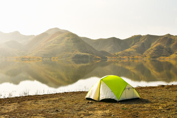 Mravaltskaro reservoir in autumn with tent and white desert canyons in background. Georgia travel destination in autumn