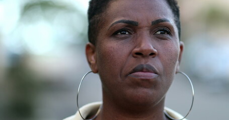 Pensive African woman walking outside in street sidewalk. Thoughtful black lady