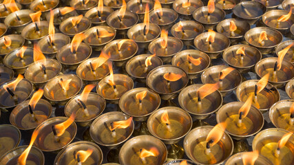 Burning prayer candles in buddhist temple, close up image