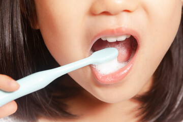 An Asian child is brushing his own teeth at home