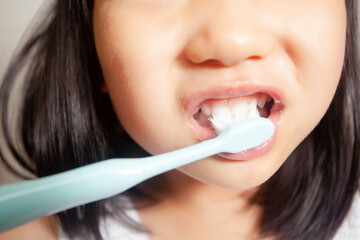 An Asian child is brushing his own teeth at home