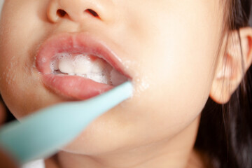 An Asian child is brushing his own teeth at home