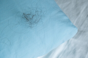 Fallen long hair on the blue pillow. Baldness and hair loss problem