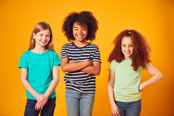 Studio Portrait Shot Of Three Children Friends Against Yellow Background