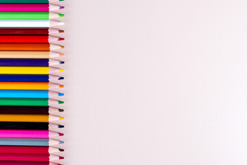 Plain background and pencils of different colors lined up